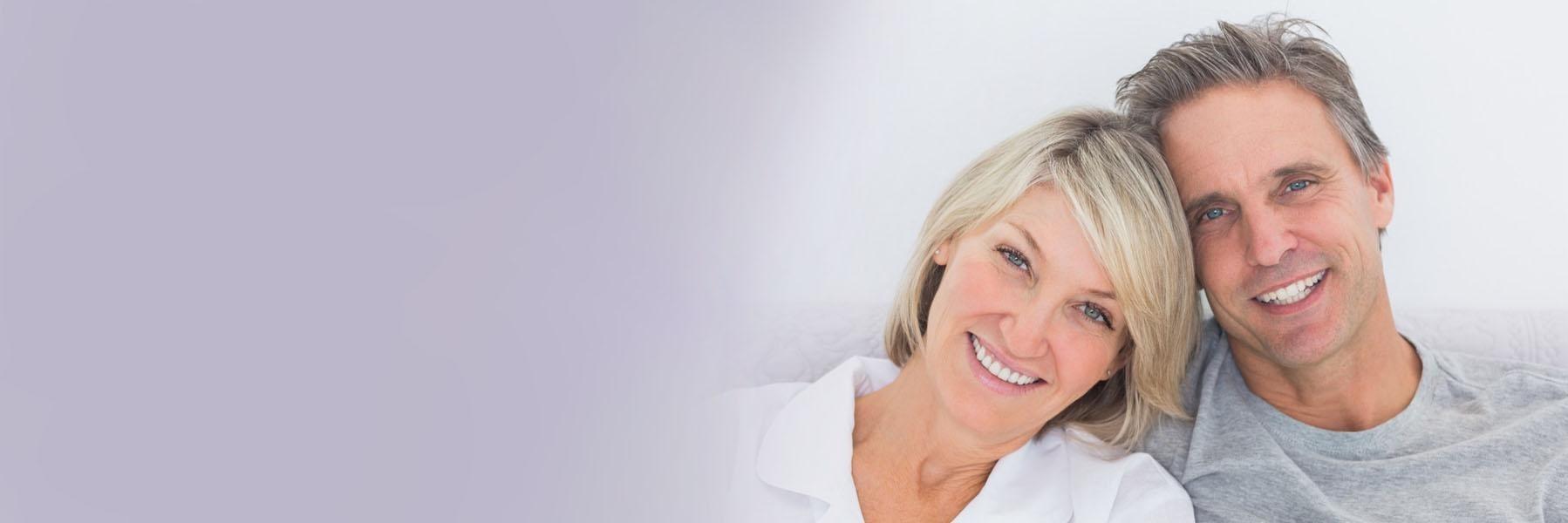 Middle-aged couple smiling & hugging l Dental implants Summerville SC