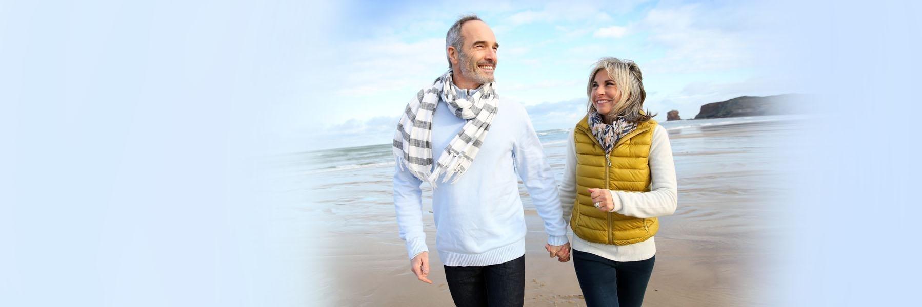 Older couple on beach smiling l Partial dentures summerville sc